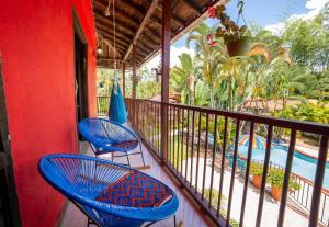 un balcón con 2 sillas azules y una piscina en LA GRANJA ECOHOTEL, en La Tebaida