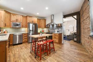 a kitchen with wooden cabinets and a table with stools at HostWise Stays - The Larryville - Amazing Bathroom, Perfect Location, Custom Build in Pittsburgh