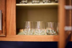 three empty wine glasses sitting on a shelf at HostWise Stays - The Raymer - Famous Artist Home, Driveway Parking, Fire Pit in Pittsburgh