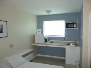 a room with a sink and a window with a microwave at Wheel Inn Motel in New Liskeard