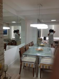 uma sala de jantar com uma mesa, cadeiras e um espelho em Apartamento fino e decorado. em Lauro de Freitas