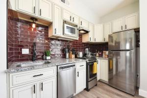 a kitchen with white cabinets and a stainless steel refrigerator at HostWise Stays - The Grandview - Great City Views - Brand New Remodel in Pittsburgh