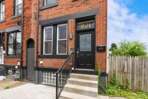 a brick house with a black door and a fence at HostWise Stays - The Peralta - Brand New, Great Kitchen, Theater Room in Pittsburgh