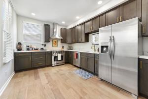una cocina con electrodomésticos de acero inoxidable y armarios de madera en HostWise Stays - The Peralta - Brand New, Great Kitchen, Theater Room, en Pittsburgh