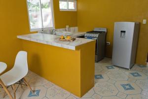 a yellow kitchen with a counter and a refrigerator at Saak Luúm Ruta Puuc in Sacalum