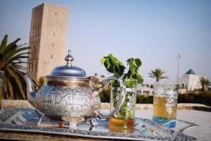 um bule de chá sobre uma mesa com dois copos de cerveja em Hassan Tower and The Marina come to you em Rabat