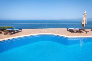 uma piscina com duas cadeiras e um guarda-sol em Amazing sea views Villa Voramar with pool em Llucmajor