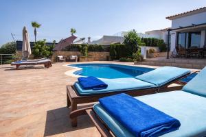 uma piscina com cadeiras almofadadas azuis ao lado de uma casa em Amazing sea views Villa Voramar with pool em Llucmajor