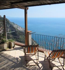 2 sedie sedute su un balcone affacciato sull'oceano di NINO'S IN NOCELLE a Positano