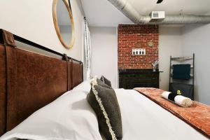 1 dormitorio con 1 cama grande y pared de ladrillo en HostWise Stays - The James Apt 1 - Patio, Free Street Parking, en Pittsburgh