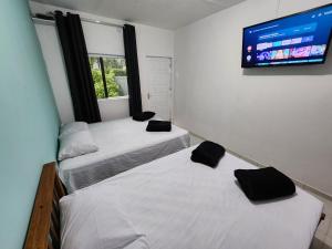 two beds in a room with a flat screen tv at Cantinho residencial in Maresias