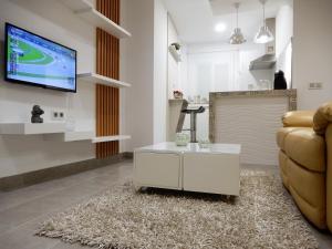 a living room with a couch and a tv on a wall at Romántico estudio centro de Algeciras in Algeciras