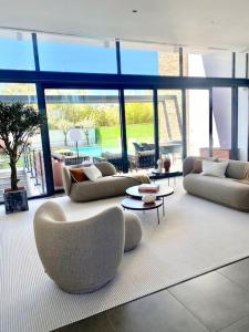 ein großes Wohnzimmer mit Sofas, Tischen und Fenstern in der Unterkunft Sunray Village T5 - Quinta do Lago/Vale do Lobo in Faro