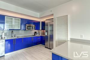 a kitchen with blue cabinets and a stainless steel refrigerator at W Hotel Ftl Beach Oceanview 2Bed 2Bath Condo Resort in Fort Lauderdale
