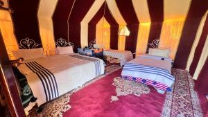 a bedroom with two beds and a rug at Sahara Luxury Camp in Zagora