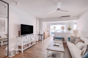 un soggiorno bianco con divano e TV di Beautiful 2 bedrooms town house. Frontline beach a Manilva