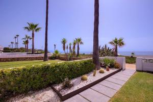 um jardim com palmeiras e o oceano ao fundo em Beautiful 2 bedrooms town house. Frontline beach em Manilva