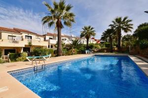 una gran piscina con palmeras y casas en Beautiful 2 bedrooms town house. Frontline beach en Manilva