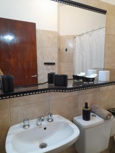 bagno con lavandino, servizi igienici e specchio di Alojamiento Belen Catamarca a Belén