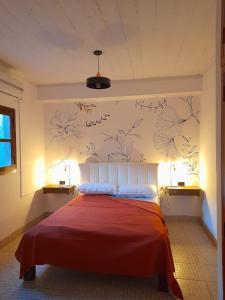 1 dormitorio con 1 cama con sábanas rojas y flores en la pared en Alojamiento Belen Catamarca en Belén
