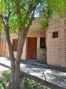 un edificio in mattoni con una porta in legno accanto ad un albero di Alojamiento Belen Catamarca a Belén
