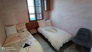 a room with two beds and a chair in it at Maison de ferme au calme jusqu'à 10 personnes in Gannay-sur-Loire