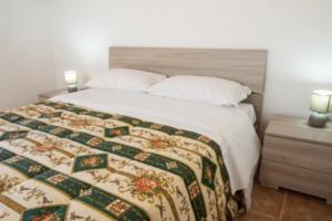 1 cama con manta y 2 lámparas en una mesita de noche en Villaggio Club Degli Ulivi en Vieste