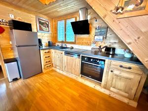 a kitchen with wooden cabinets and a stainless steel refrigerator at Refuge des Cimes in Saint-Laurent-en-Grandvaux