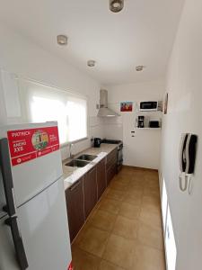 cocina con nevera blanca y fregadero en APARTAMENTOS TEMPORARIOS EN LA PLATA ( minimo de alquiler 3 dias- La reserva solo se confirma con mensaje al Whasapp de la foto) . Avenida 19 casi 42 La Plata en La Plata