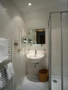 a white bathroom with a sink and a shower at Hotel Gasthof Moosleitner in Freilassing