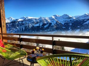 uma mesa e cadeiras numa varanda com montanhas cobertas de neve em Hotel Gloria em Beatenberg