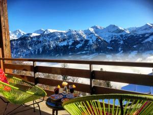a table and chairs on a balcony with snow covered mountains at Hotel Gloria in Beatenberg
