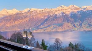 two wine glasses sitting on a ledge overlooking a lake at Hotel Gloria in Beatenberg