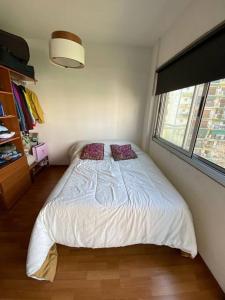 um quarto com uma cama com duas almofadas e uma janela em Deleuxe Studio en Caballito em Buenos Aires