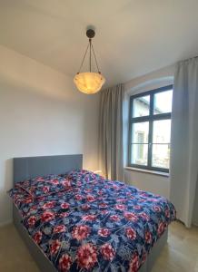ein Schlafzimmer mit einem Bett mit einer bunten Decke und einem Fenster in der Unterkunft Altes Pfarrhaus in Papstdorf