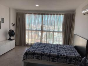 1 dormitorio con cama y ventana grande en LOFT PRAIA GRANDE -, en Arraial do Cabo