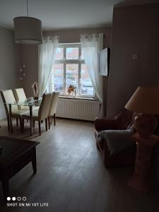 ein Wohnzimmer mit einem Tisch, Stühlen und einem Fenster in der Unterkunft Ferienwohnung Henny in Wismar