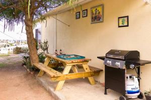 a picnic table next to a tree and a grill at Hellshire Portmore Vacation Home in Portmore