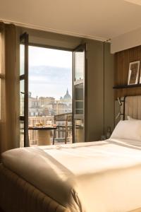 pokój hotelowy z łóżkiem i dużym oknem w obiekcie Hôtel Dame des Arts w Paryżu