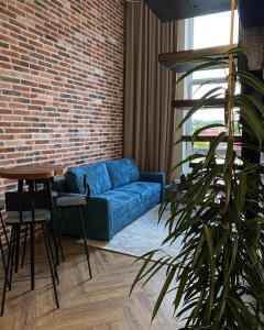 ein Wohnzimmer mit einem blauen Sofa und einer Ziegelwand in der Unterkunft Old Slabada Loft Kaunas in Kaunas