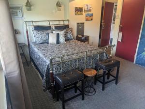 een slaapkamer met een bed en twee krukken erin bij The Parks Inn in Three Rivers
