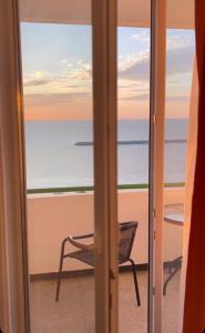 a door to a balcony with a chair looking out at the ocean at Hotel Cosmos in Eforie Sud