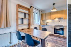 a kitchen with a wooden table and blue chairs at Sweet Home Apartments in Tösens