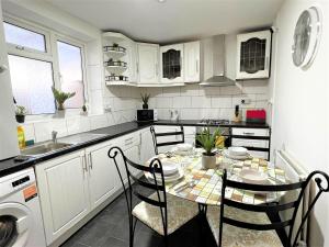 a kitchen with white cabinets and a table and chairs at Stepney Green Comfy Double bed rooms 14 in London