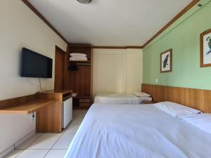 カルダス・ノバスにあるFlet Golden Dophinのベッド2台、薄型テレビが備わるホテルルームです。