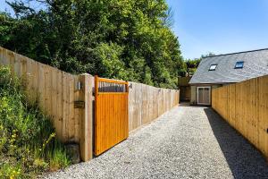 a fence with a wooden gate next to a house at BISHOPS TAWTON SNOWDROP COTTAGE 3 Bedrooms in Bishops Tawton