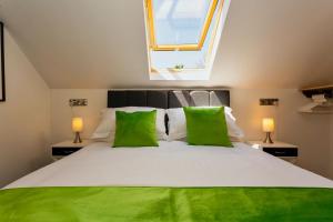 a bedroom with a large white bed with green pillows at BISHOPS TAWTON SNOWDROP COTTAGE 3 Bedrooms in Bishops Tawton