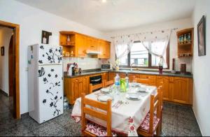 een keuken met een tafel en een witte koelkast bij Casa Rural Yeyo en el cráter del volcán in Tinguatón +20 foto's