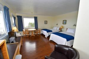 une chambre d'hôtel avec deux lits et une chaise dans l'établissement Motel Nouvel Horizon, à Percé