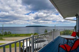 a porch with two chairs and a table and the ocean at Motel Nouvel Horizon in Perce